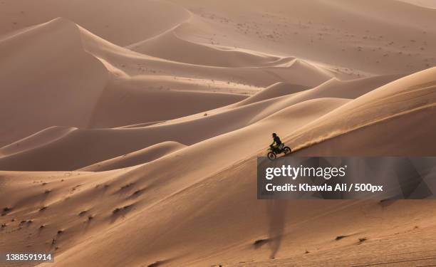 man riding motorcycle on sand dune in desert - atv sand dune stock pictures, royalty-free photos & images