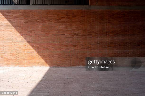 front view of brick wall and floor partially illuminated by sunlight - brick road stock pictures, royalty-free photos & images