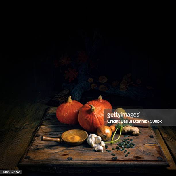 high angle of pumpkin and assorted vegetables on wooden table against black background - organisch fotografías e imágenes de stock
