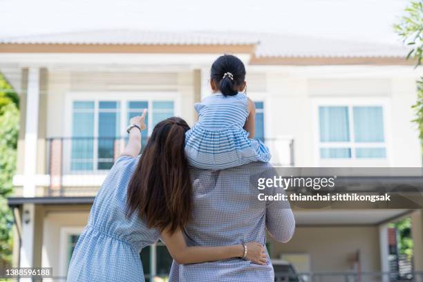 back view of happy family moving into new house admiring their house. - good move concept stockfoto's en -beelden