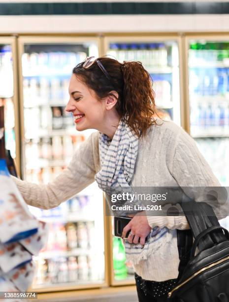 frau auf dem sprung in einem lebensmittelgeschäft einzelhandel schnellmarkt oder flughafen auswahl etwas aus einem regal - airport shopping stock-fotos und bilder