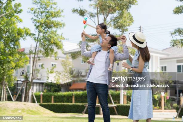 image of asian family has fun playing piggyback their daughter in the field at the park. - park couple piggyback stock pictures, royalty-free photos & images