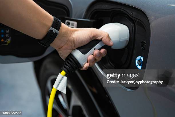 hand charging modern electric car - elektrische auto stockfoto's en -beelden