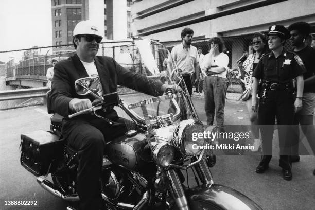 Canadian actor and comedian Dan Aykroyd sits on a Harley Davidson motorcycle outside an event celebrating the construction of the Hard Rock Cafe on...