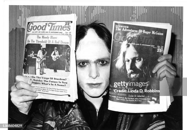 Wearing face paint and a distinctive part-shaved haircut, English singer Peter Gabriel of Genesis holds up November copies of Good Times, the New...