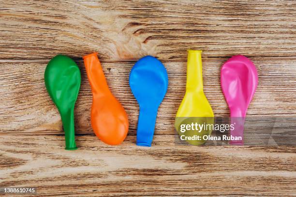 deflated balloons on wooden background. - deflated stock-fotos und bilder