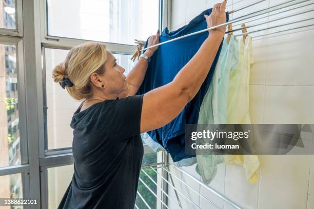 housewife puts clothes to dry on the clothesline - women in wet tee shirts stock pictures, royalty-free photos & images
