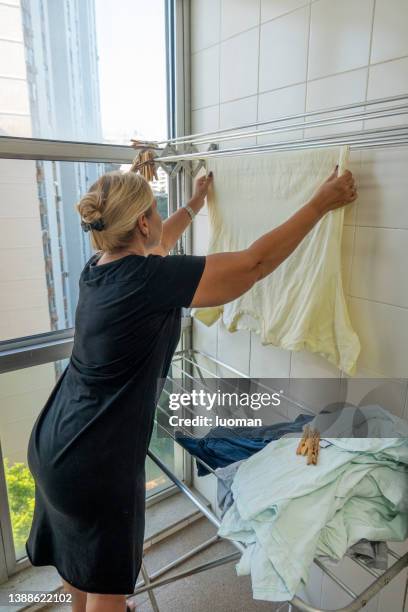 housewife puts clothes to dry on the clothesline - women in wet tee shirts stock pictures, royalty-free photos & images