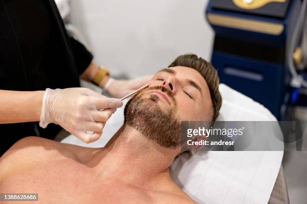 hombre en el spa depilándose la barba - esteticista fotografías e imágenes de stock
