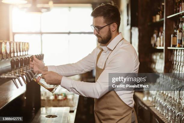 bartender pouring beer - beer tap stockfoto's en -beelden