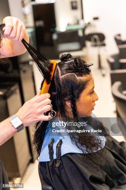 curly-haired female client during haircut in modern luxury hairdressing salon - hair color saloon stock pictures, royalty-free photos & images