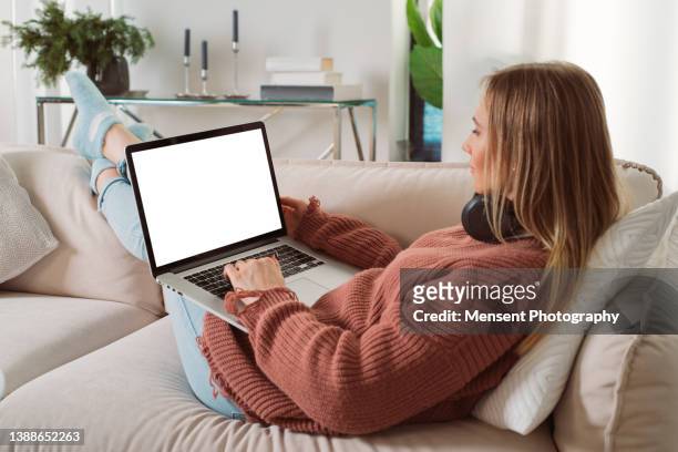 young casual woman lying on couch at home using laptop in white screen - touchpad bildbanksfoton och bilder