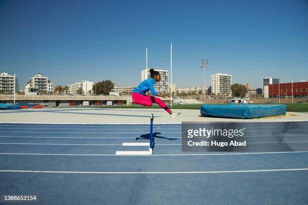 a young woman jumping hurdles. - sprint planning stock pictures, royalty-free photos & images