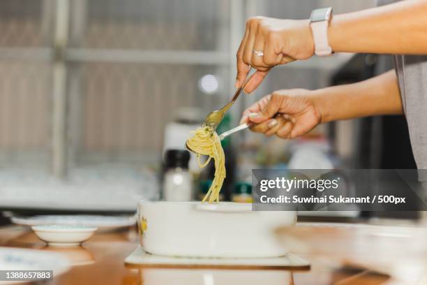 woman eating spaghetti carbonara with folk and spoon at dinner table,thailand - carbonara stock pictures, royalty-free photos & images