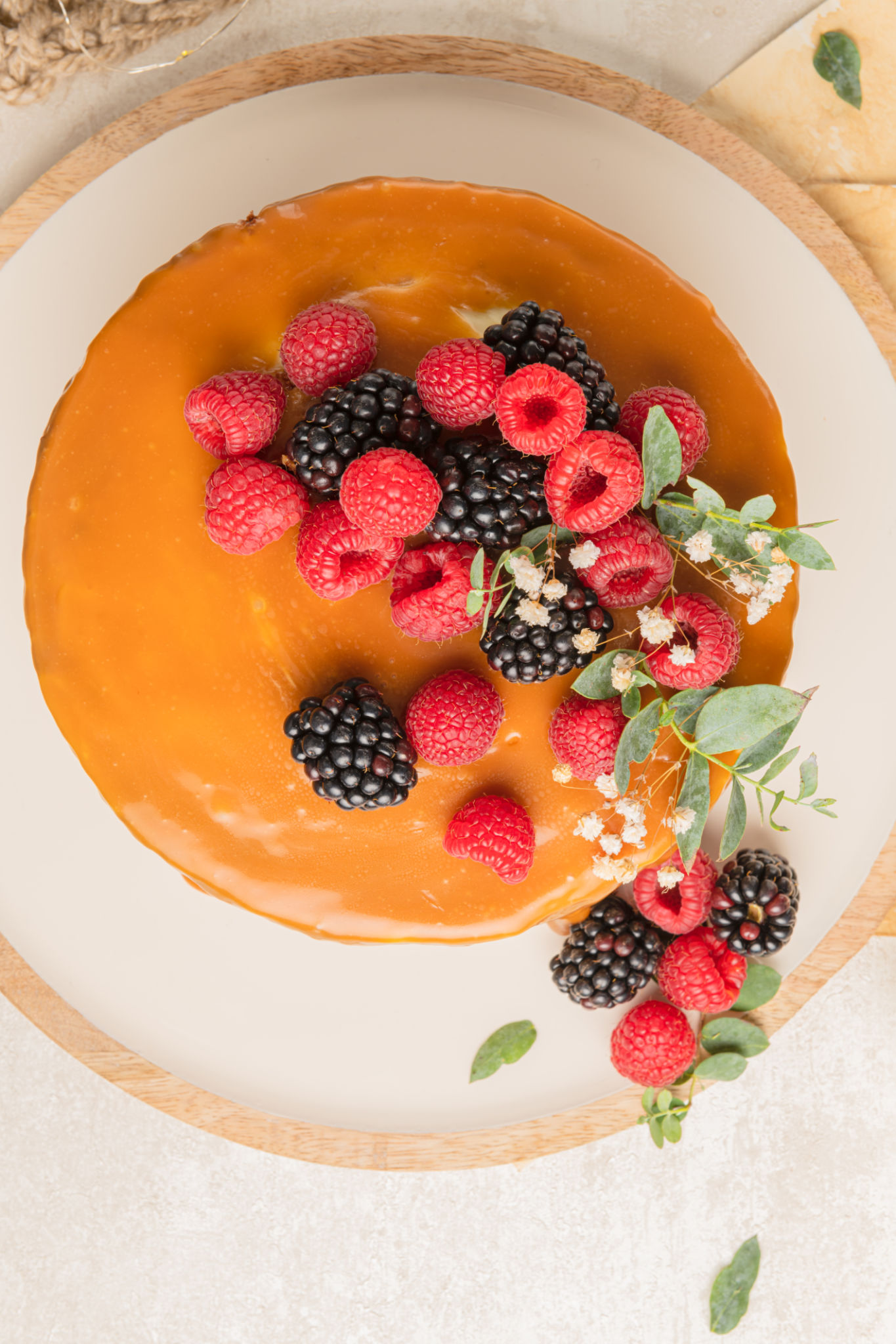 Delicious chocolate cake topped with mascarpone cream and salted caramel. Decorated with red fruits. Light background Delicious chocolate cake topped with mascarpone cream and salted caramel. Decorated with red fruits. Light background