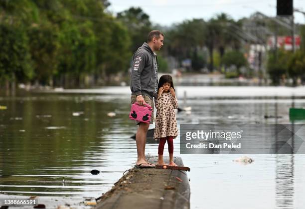 Father and his young daughter inspect a flooded street on March 31, 2022 in Lismore, Australia. Evacuation orders have been issued for towns across...