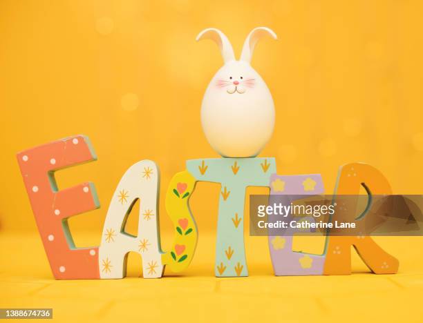 vibrant easter background with easter decoration and a cute easter bunny in a yellow setting - easter sunday stock pictures, royalty-free photos & images