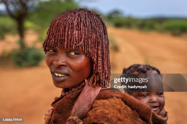 frau aus dem stamm der hamer, die ihr baby in äthiopien trägt, afrika - hamer stock-fotos und bilder