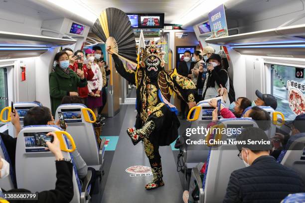 Performer stages Sichuan opera face changing show for passengers on a train on March 30, 2022 in Guiyang, Guizhou Province of China. Ring road fast...