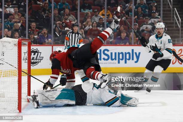 Nick Ritchie of the Arizona Coyotes falls over goaltender James Reimer of the San Jose Sharks during the first period of the NHL game at Gila River...