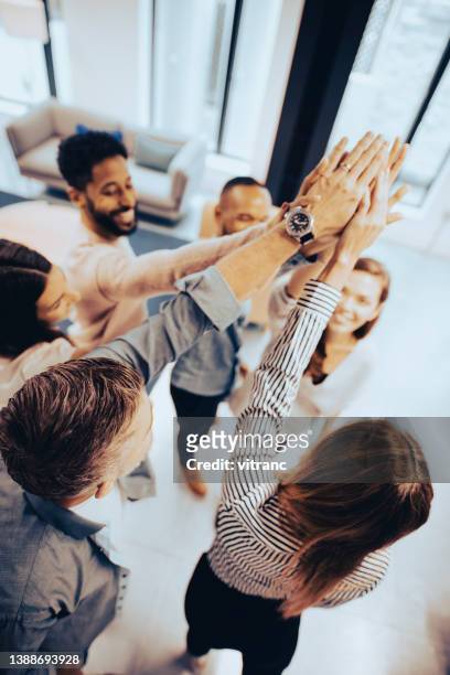lavorare insieme per vincere insieme - high five business foto e immagini stock