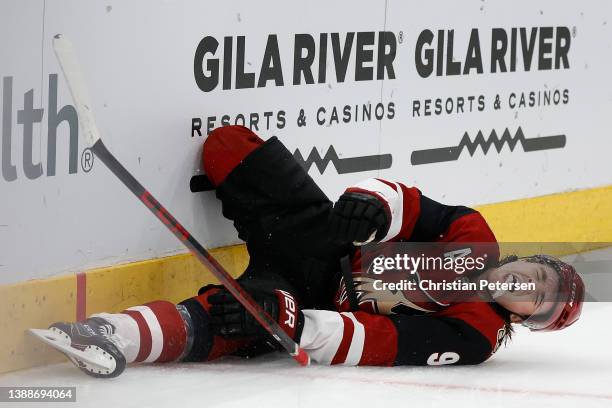 Clayton Keller of the Arizona Coyotes reacts in pain after crashing into the boards during the third period of the NHL game against the San Jose...