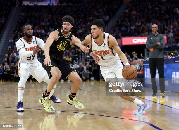 Devin Booker of the Phoenix Suns is guarded by Klay Thompson of the Golden State Warriors in the second half at Chase Center on March 30, 2022 in San...