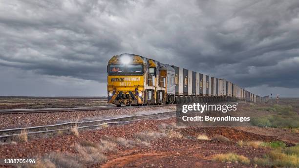 container freight train in sparse desert under stormy skies - rail freight stock pictures, royalty-free photos & images