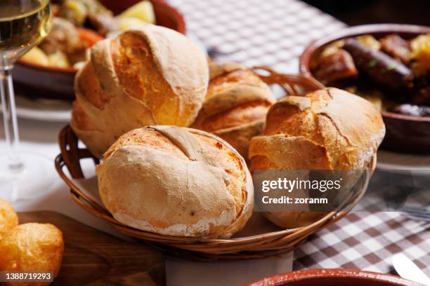perfekt gebackene brötchen mit rissiger kruste im weidenkorb auf dem restauranttisch - baked goods stock-fotos und bilder