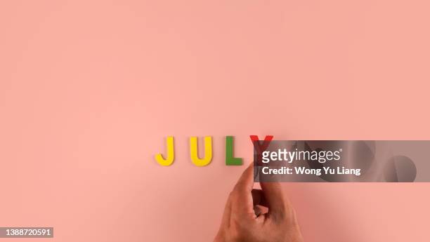 hand holding , july word block in pink blackground - hello may stock pictures, royalty-free photos & images