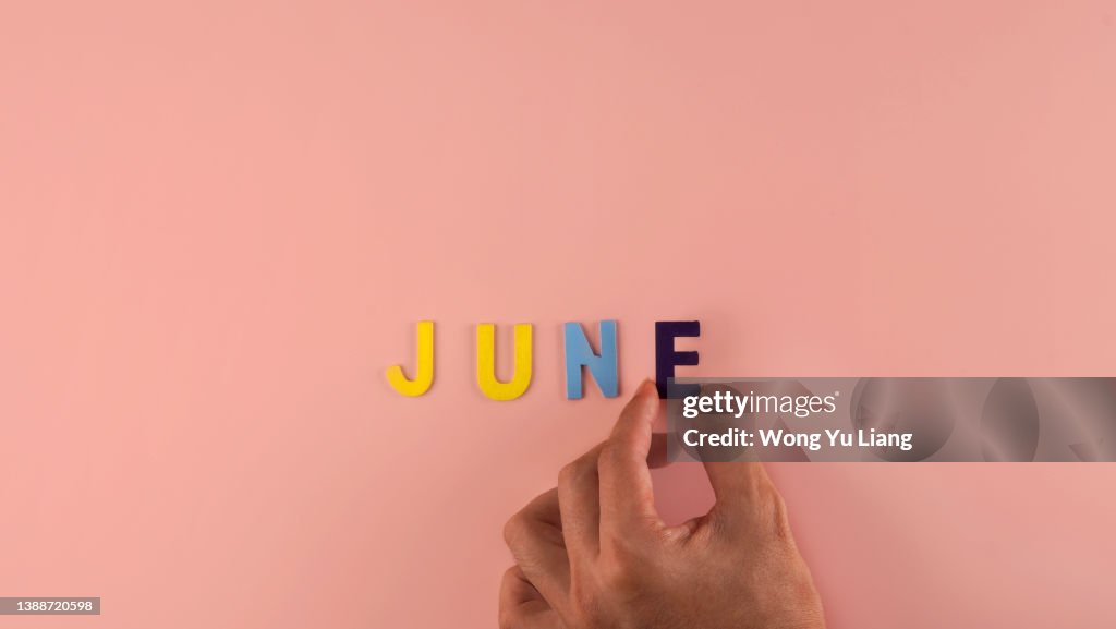 Hand holding , June word block in pink blackground