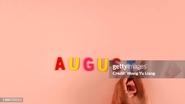 hand holding , august  word block in pink background - august stock-fotos und bilder