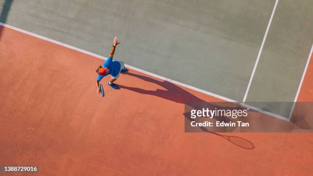 drone point of view asian tennis player serving the ball with shadow directly above - tennis quick imagens e fotografias de stock