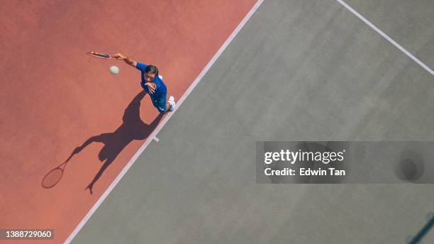 drone punto di vista asian tennis player serving the ball con ombra direttamente sopra - tennis shadow foto e immagini stock