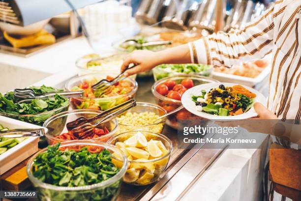 woman choosing food for breakfast at hotel restaurant. woman taking food from a buffet line. - colazione hotel foto e immagini stock