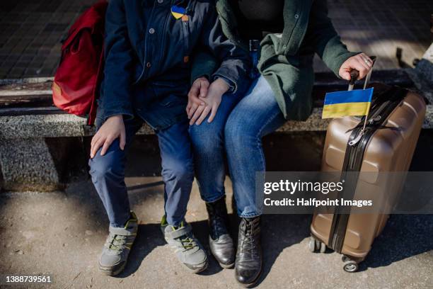 low section of ukrainian refugee family sitting in station when waiting to leave ukraine due to the russian invasion of ukraine. - 軍事演習 ストックフォトと画像