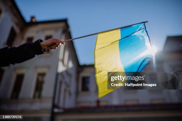 people holding ukrainian flag and protesting against russian invasion in ukraine in streets. - russische-invasion-in-die-ukraine stock-fotos und bilder