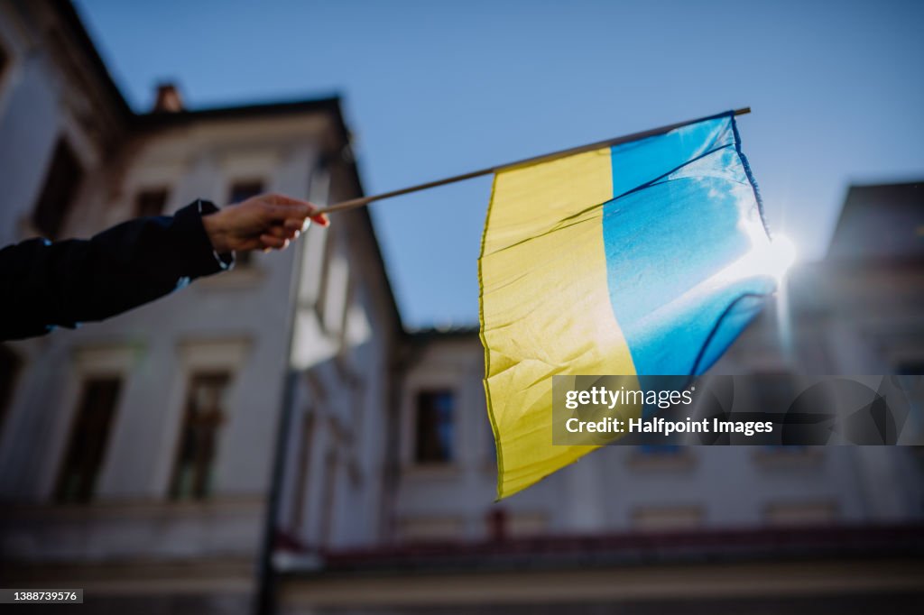 People holding Ukrainian flag and protesting against Russian invasion in Ukraine in streets.