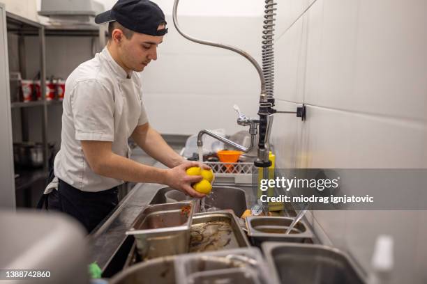 männlicher angestellter, der die zitrone über der spüle in der küche wäscht - untidy sink stock-fotos und bilder