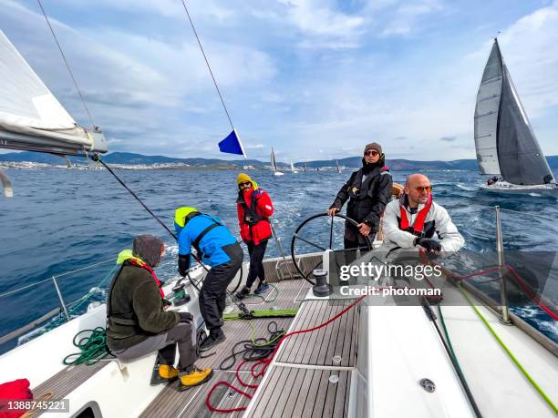 group of male sailors on deck of a sailboat racing at regatta with skipper at rudder - rudder stock pictures, royalty-free photos & images
