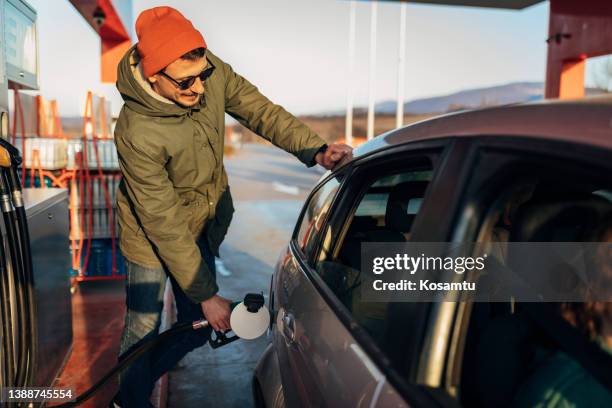 a young loving couple fills a fuel tank at a gas station - gasoline pouring stock pictures, royalty-free photos & images