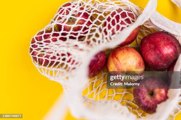 apples in a reusable shopping bag on yellow background. - plastic free stock pictures, royalty-free photos & images