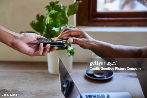 man using a bank card and contactless terminal to pay for a cafe purchase - tap card stock pictures, royalty-free photos & images