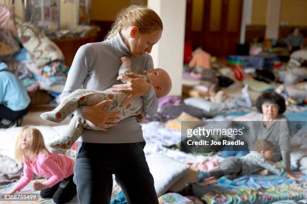 Xenia comforts her baby Alexander while they rest at a temporary refugee center setup at the main train station on March 31, 2022 in Lviv, Ukraine....