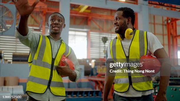 two heavy industry engineers take off hard hats walk in steel metal manufacturing factory and have a discussion. - color enhanced stock pictures, royalty-free photos & images