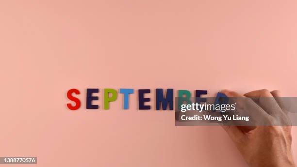 hand holding , september  word block in pink background - septiembre fotografías e imágenes de stock