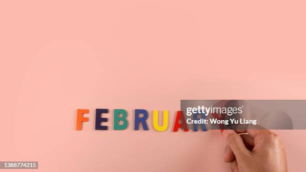 february word block in pink background with hand - febrero fotografías e imágenes de stock