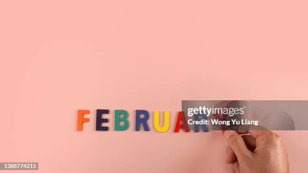 february word block in pink background with hand - february stockfoto's en -beelden