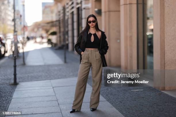 Antonia Sophie seen wearing a brown sunglasses, a black LeGer crop top, gold necklaces, a black leather blazer from LeGer, a beige wide leg pants...