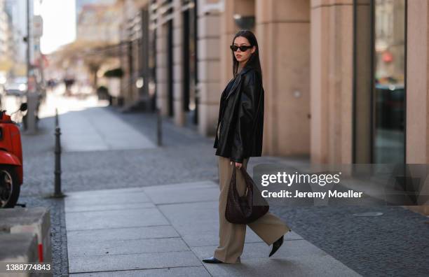Antonia Sophie seen wearing a brown sunglasses, a black LeGer crop top, gold necklaces, a black leather blazer from LeGer, a beige wide leg pants...